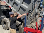 mechanic shown standing alongside Pavementgroup's Amerispreader chip spreader and demonstrates how to attach it to the truck frame