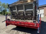 Chip spreader filled with stone aggregate attached to back of dump truck