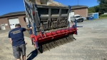 stone chip spreader broadcasting aggregate shown with a man walking alongside controlling the main flow gate by pulling on steel arm lever