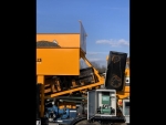 Pugmill mixer by Olympus shown with its 7cy loading bin, loaded with aggregate, preparing to produce cold mix asphalt