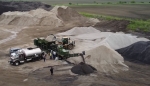 industrial pugmill system shown mixing two stone sizes with asphalt emulsion in the pugmill mixer and discharging from folding stacking conveyor to quarry pile