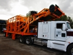 Surge bin by Olympus shown attached to tractor with unloading conveyor extending over cab